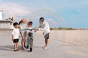 Family on the beach they are enjoy bicycle. Happy father, mother and son, daughter enjoying road trip the summer holidays.Parents