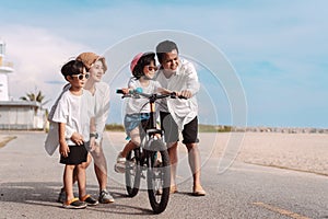 Family on the beach they are enjoy bicycle. Happy father, mother and son, daughter enjoying road trip the summer holidays.Parents