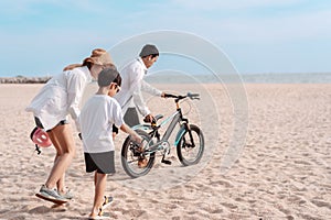 Family on the beach they are enjoy bicycle. Happy father, mother and son, daughter enjoying road trip the summer holidays.Parents