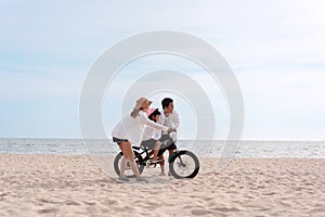 Family on the beach they are enjoy bicycle. Happy father, mother and son, daughter enjoying road trip the summer holidays.Parents