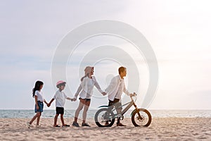 Family on the beach they are enjoy bicycle. Happy father, mother and son, daughter enjoying road trip the summer holidays.Parents