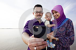 Family at beach making a self portrait with a mobile phone
