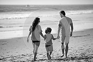Family on the beach. People having fun on summer vacation. Father, mother and child holding hands against blue sea.