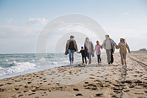 big multigenerational family walking together on beach photo