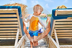 Family at beach on wooden sun bed loungers