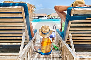 Family at beach on wooden sun bed loungers