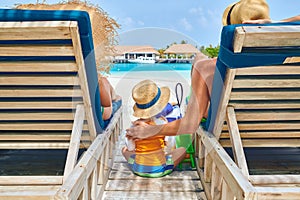 Family at beach on wooden sun bed loungers