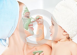 Family beauty treatment in bathroom. mother and daughter baby girl make mask for face skin