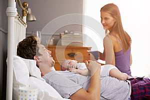 Family In Bed Holding Sleeping Newborn Baby Daughter