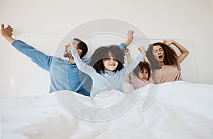 Family, bed and yawn in morning wake up, relax or sleep together with arms up at home. Calm parents, children and