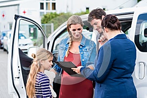 Family being advised by salesperson buying car photo