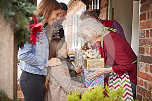 Family Being Greeted By Grandparents As They Arrive For Visit On Christmas Day With Gifts photo