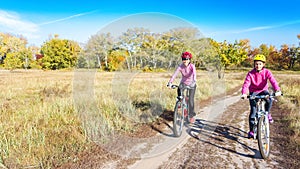 Family on bikes autumn cycling outdoors, active mother and kid on bicycles, aerial view of happy family with child in fall park