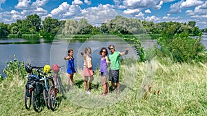 Family on bikes cycling outdoors, active parents and kids on bicycles, aerial top view of happy family with children