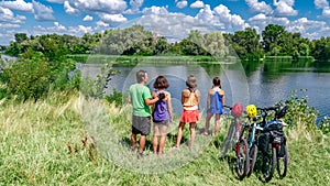 Family on bikes cycling outdoors, active parents and kids on bicycles, aerial top view of happy family with children near river