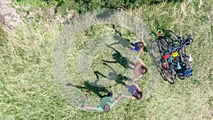 Family on bikes cycling outdoors, active parents and kids on bicycles, aerial top view of happy family with children near river