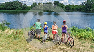 Family on bikes cycling outdoors, active parents and kids on bicycles, aerial view of happy family with children relaxing