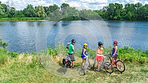 Family on bikes cycling outdoors, active parents and kids on bicycles, aerial view of happy family with children relaxing