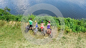 Family on bikes cycling outdoors, active parents and kids on bicycles, aerial view of happy family with children relaxing