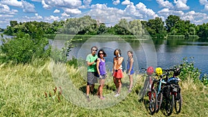 Family on bikes cycling outdoors, active parents and kids on bicycles, aerial view of happy family with children relaxing