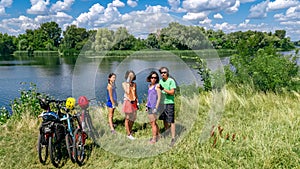 Family on bikes cycling outdoors, active parents and kids on bicycles, aerial view of happy family with children relaxing