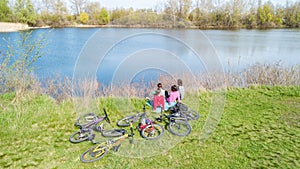 Family on bikes cycling outdoors, active parents and kids on bicycles, aerial view of happy family with children relaxing