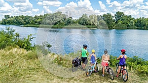 Family on bikes cycling outdoors, active parents and kids on bicycles, aerial view of happy family with children relaxing