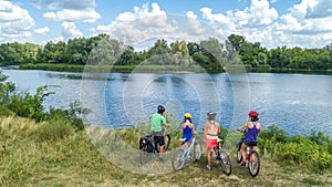 Family on bikes cycling outdoors, active parents and kids on bicycles, aerial view of happy family with children relaxing