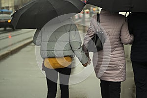 Family with black umbrellas. People rain. Parents with their daughter walk around the city