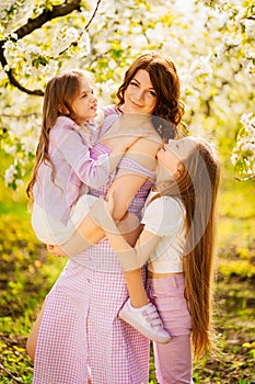 A family in a blossoming spring garden. Happy mom and two daughters.