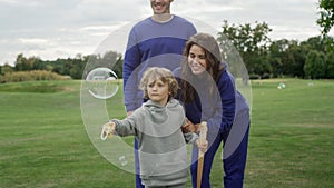 A family blows soap bubbles together in the park.