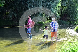 Family bonding. Anglers. Happy weekend concept. Man teaching kids how to fish in river. Portrait of happy little son photo