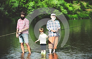 Family bonding. Grandfather, father and grandson fishing together. Little boy on a lake with his father and grandfather.