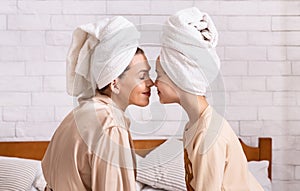 Family bonding time. Mom and daughter in bath towels touching noses at home