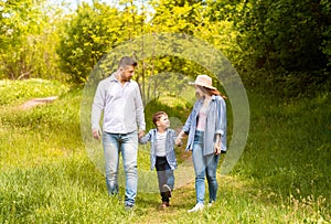 Family bonding times. Young parents and their son on a walk together in countryside