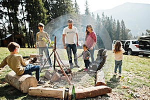 Family bonfire in mountain.Four kids camping. Bbq marshmallow. Autumn hike and camp weather. Warming and cooking near flame