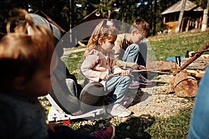 Family bonfire in mountain. Frying sausages. Mother with four kids camping. Autumn hike and camp weather. Warming and cooking near