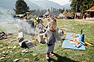 Family bonfire in mountain. Mother with four kids camping. Autumn hike and camp weather. Warming and cooking near flame together