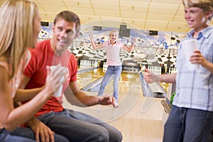 Family in bowling alley cheering and smiling