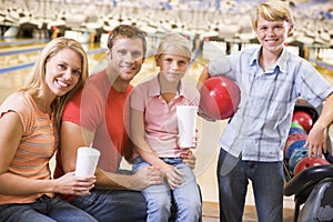 Family in bowling alley with drinks smiling