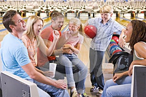 Family in bowling alley with two friends cheering