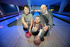 Family in bowling club and shows hands of ok