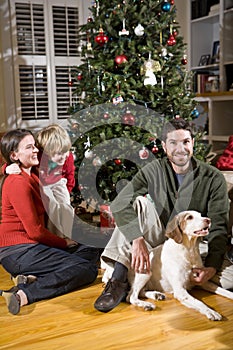 Family with boy and dog by Christmas tree