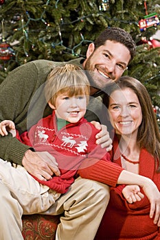 Family with boy sitting in front of Christmas tree