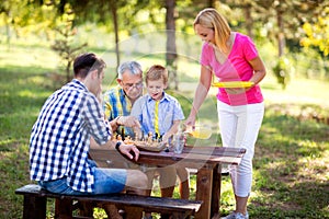 Family have break in nature play chess,