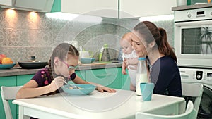 Family breakfast at morning. Girl eating corn flakes with milk at kitchen table