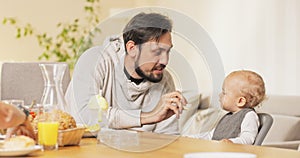 During a family breakfast at the table, a smiling man kisses his child on the