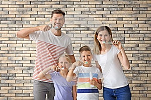 Family brushing teeth against brick wall