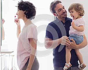 Family Brushing Teeth In Bathroom Mirror