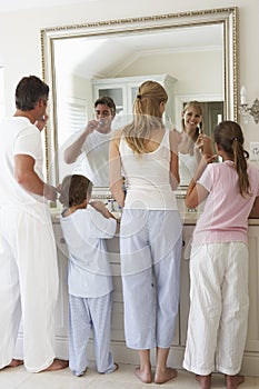 Family Brushing Teeth In Bathroom Mirror